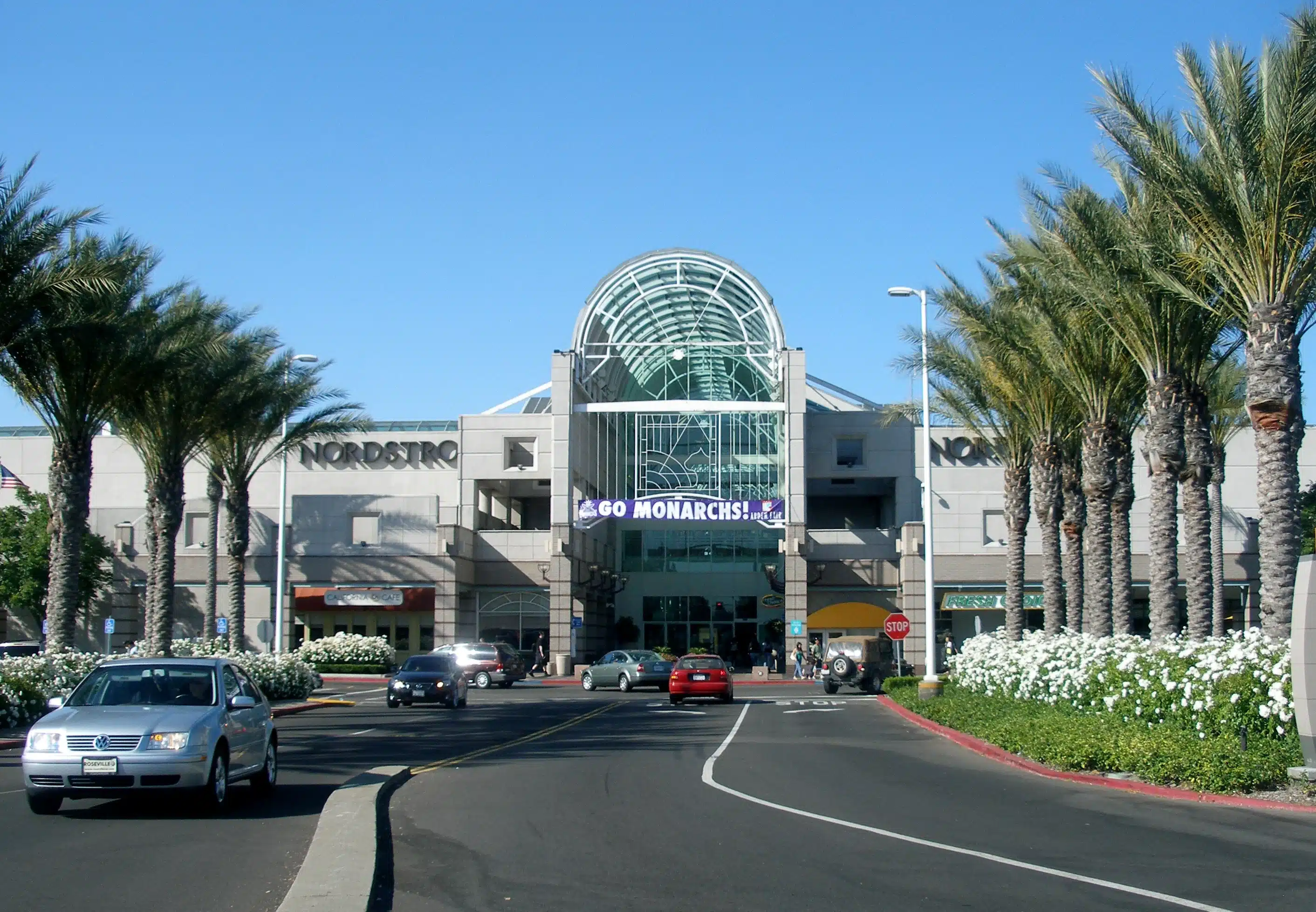 Arden Fair Mall entrance with palm trees and traffic in Arden Arcade, CA